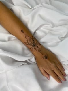 a woman's arm with a flower tattoo on the left side of her hand