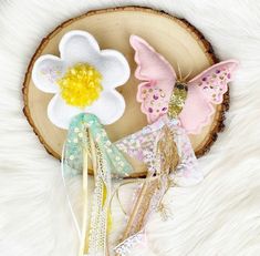 three hair clips with flowers and butterflies on them sitting on top of a white furry surface