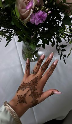 a woman's hand with hendix on it and flowers in the background