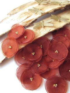 several red flowers are sitting on top of some driftwood sticks with gold flecks