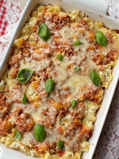 a casserole dish with meat, cheese and basil leaves on the top is ready to be eaten