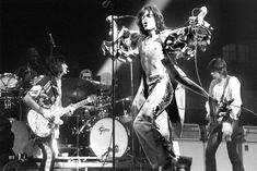 the rolling stones performing on stage in front of microphones and guitar players, with one man