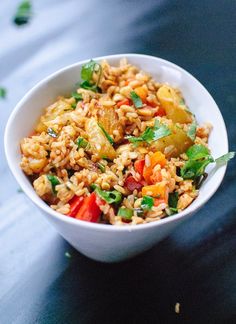 a white bowl filled with rice and veggies on top of a black table