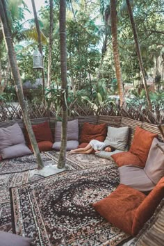 a woman laying on top of a couch in the middle of a room filled with trees