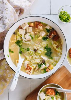 a bowl of chicken noodle soup on a table with other bowls and spoons