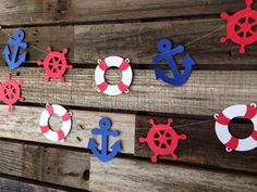 red, white and blue paper cutouts are hung on a wooden wall with life preservers