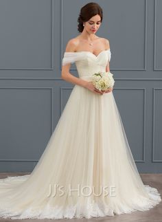 a woman in a white wedding dress standing next to a blue wall and holding a bouquet