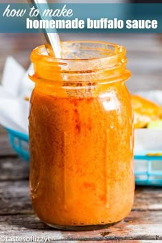 a jar filled with homemade buffalo sauce on top of a wooden table