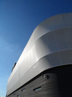 the side of a large building with a clock on it's face and sky in the background