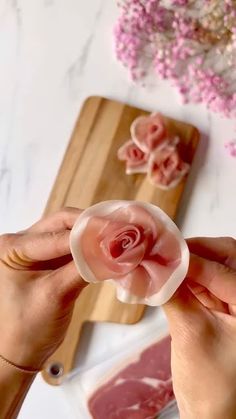 a person holding a piece of food in front of some other foods on a cutting board