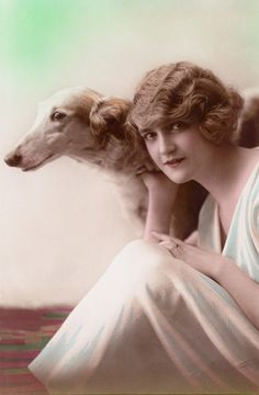 an old fashion photo of a woman with a dog in her lap and another dog behind her