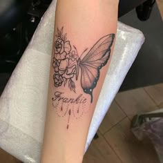 a woman's arm with a butterfly and flowers tattoo on the left side of her arm