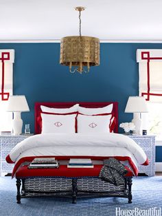 a bedroom decorated in red, white and blue with a chandelier hanging from the ceiling