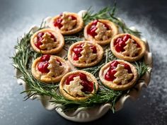 several small pastries are arranged in a dish on a black counter top with rosemary sprigs