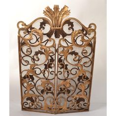 an ornate gold colored metal screen with flowers and leaves on the sides, set against a white background