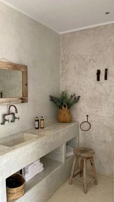 a bathroom with two sinks, a stool and a mirror on the wall next to it