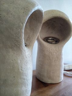 two white vases sitting on top of a wooden table