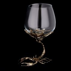 a wine glass sitting on top of a black table next to a dragon's head