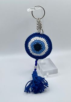 a blue and white crocheted key chain with an evil eye on the front