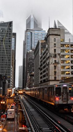 a train traveling down tracks next to tall buildings in a city with traffic lights on