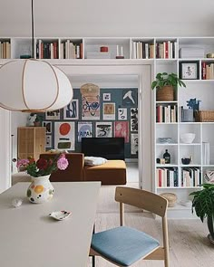 a living room filled with furniture and bookshelves next to a dining table in front of a window