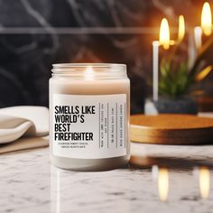 a candle that reads smells like world's best firefighter sits on a marble countertop