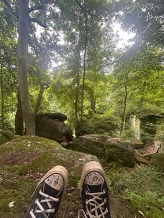 someone's feet are standing on a rock in the woods