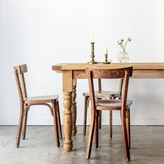 a wooden table with two chairs and a vase on it's end next to a candle holder