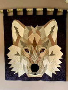 a quilt made to look like a wolf's head is hanging on the wall