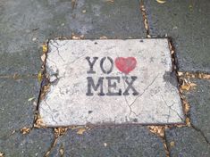 a cement sign with the words you love mex painted on it and a heart