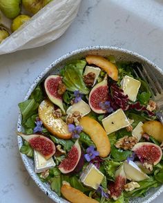 a salad with figs, cheese and nuts in a bowl on a marble table