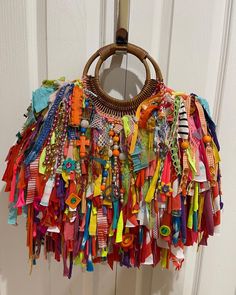 a basket hanging from the side of a door covered in colorful ribbons and beads,