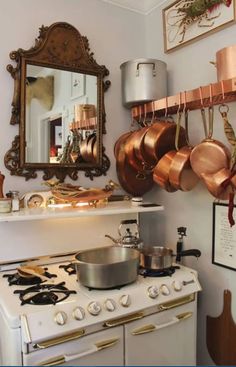 a kitchen with copper pots and pans hanging on the wall next to an oven