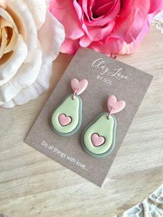 a pair of earrings sitting on top of a table next to a pink flower and card