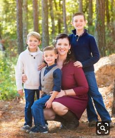 a woman and two boys are posing for a family photo in the woods with trees