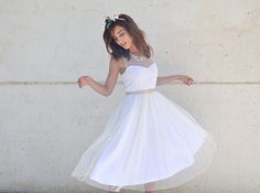 a young woman in a white dress is posing for the camera with her hand on her hip