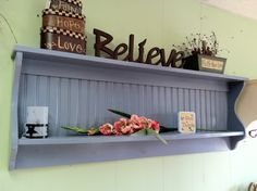 there is a shelf with flowers on it and a sign above it that says believe