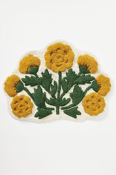 an embroidered patch with yellow flowers and leaves on white background, in the shape of a cloud