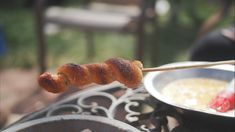 a person is holding a skewer with food on it next to a bowl