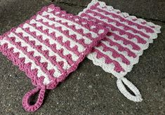 a crocheted pink and white blanket laying on the ground next to a pair of scissors