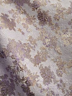 a purple and gold floral pattern on a white fabric with metallic foilwork, closeup