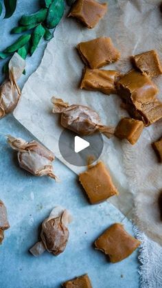 some pieces of peanut butter on a piece of parchment paper next to leaves and flowers