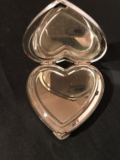 two heart shaped mirrors sitting on top of a black tableclothed surface, one is open and the other is closed