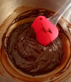 a red spatula in a metal bowl filled with chocolate