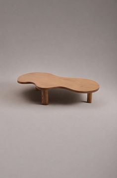 a wooden table sitting on top of a white floor next to a gray wall in front of it