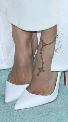 a close up of a person's foot with a cross tattoo on the ankle