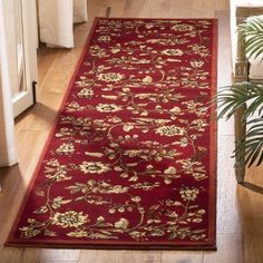 a red rug is on the floor next to a plant