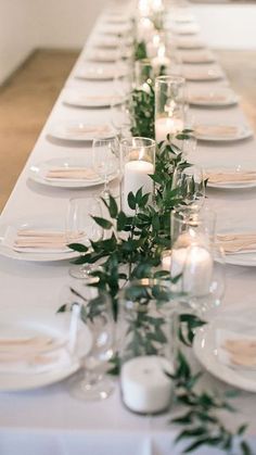 a long table is set with candles and greenery for an elegant dinner or party