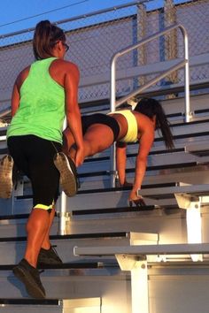 two women in yellow shorts are on the bleachers and one is leaning over