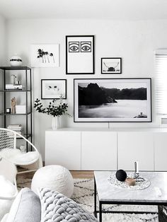 a living room filled with white furniture and pictures on the wall above it's coffee table